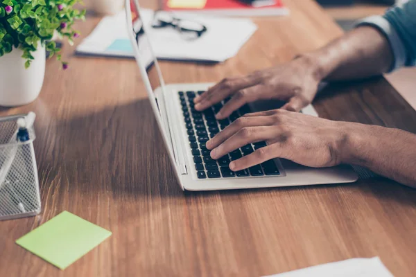 Seitenprofil beschnitten Foto von afroamerikanischen Geschäftsmann Hände auf der Tastatur des Laptops auf einer hölzernen Tischplatte, mit der Eingabe der Daten beschäftigt — Stockfoto