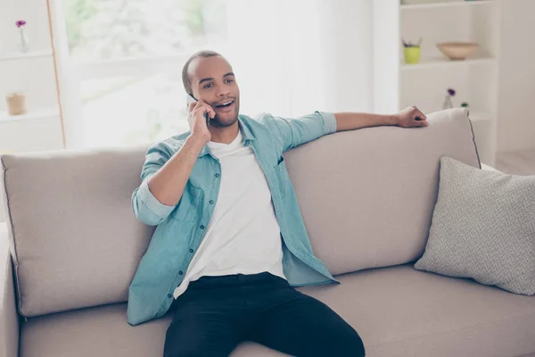 Joven estudiante africano sonriente está hablando por teléfono, sentado — Foto de Stock