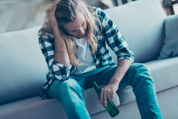 Frustrierter einzelner junger Mann sitzt auf einem Sofa und trinkt ein — Stockfoto