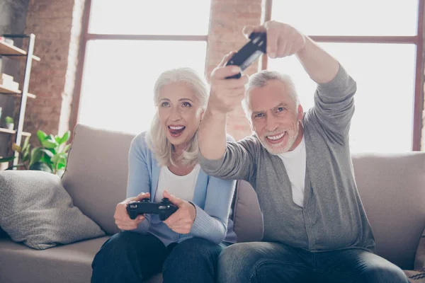 Middle-aged couple excited passionate about car racing game, sit