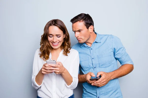 Retrato de casal encantador com telefones inteligentes em mãos, c alegre — Fotografia de Stock