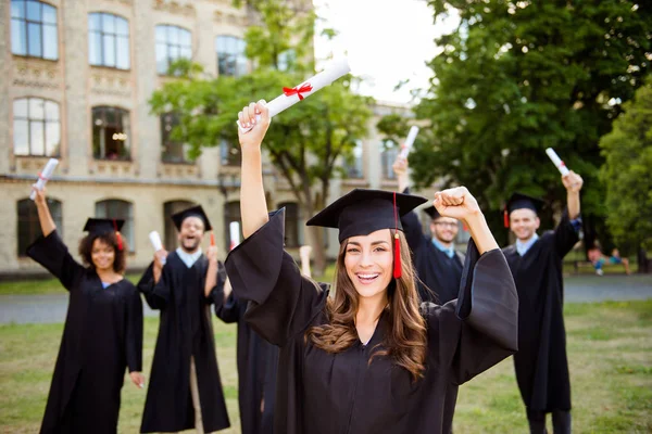 ¡Lo logramos! Feliz chica graduada sonríe, grupo de sus amigos clas —  Fotos de Stock