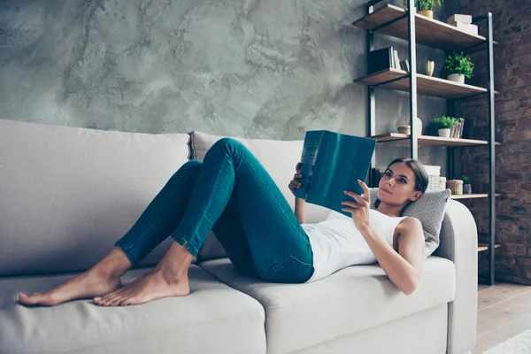 Mooie, charmante vrouw in spijkerbroek leggen op Bank, in de hand houden — Stockfoto