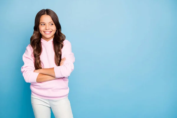 Foto de la señora bastante pequeña largo peinado ondulado con las manos cruzadas toothy sonriendo buscando espacio vacío desgaste sudadera con capucha casual suéter rosa aislado color azul fondo — Foto de Stock