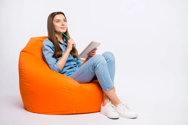 Full size profile side photo of focused girl sit on lounge chair think want create fiction story feel curious try guess ponder wear denim clothes sneakers isolated over white color background — Stok fotoğraf