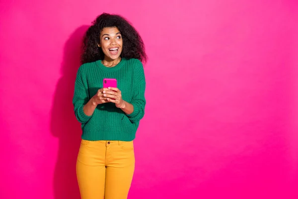 Portrait de funky drôle inspiré fille hipster utiliser son smartphone eu notification feednews de blogueur penser imaginer porter vert élégant pull pantalon jaune isolé sur fond de couleur rose — Photo