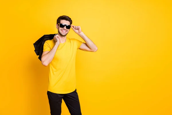 Foto di bel ragazzo che tiene borse boutique fare shopping all'estero persona di classe sicura di sé indossare casual t-shirt pantaloni isolato colore giallo sfondo — Foto Stock