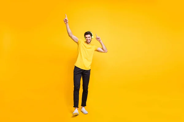 Foto de cuerpo entero tamaño de hombre atractivo alegre guapo usando camiseta amarilla pantalones negros bailando con auriculares usados aislados sobre fondo de color vibrante —  Fotos de Stock