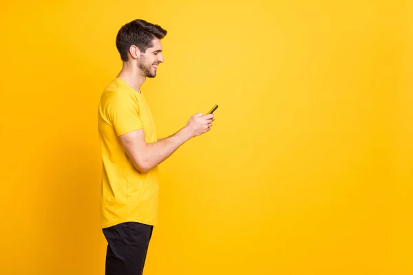 Profile photo of youth handsome guy holding telephone chatting friends discussing future students party wear casual t-shirt isolated yellow color background — ストック写真