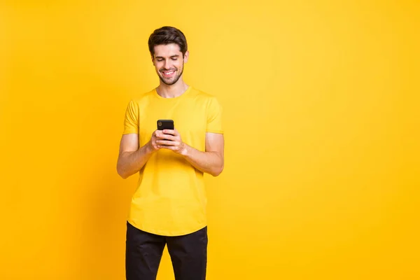 Foto de homem atraente bonito navegando através de seu telefone em busca de novas informações de leitura feednews isolado sobre fundo de cor vívida amarelo — Fotografia de Stock