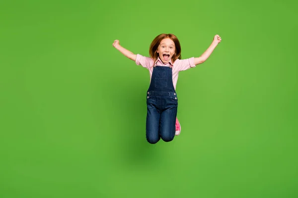 Foto de comprimento total de alegre muito pouco estudante saltando alto regozijando férias de verão começando a usar jeans casuais camisa rosa geral isolado fundo verde — Fotografia de Stock