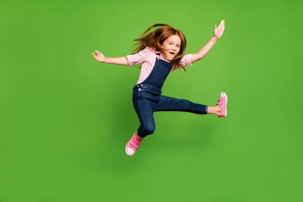 Фото веселих смішних досить маленьких школярів, які стрибають з високими бойовими вправами тренування носіння повсякденної джинсової загальної рожевої сорочки ізольований зелений фон — стокове фото