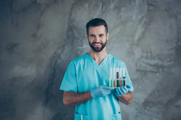회색 벽 콘크리트 색 배경 위에 균일하게 고립된 많은 테스트 튜브를 들고 가렵게 미소짓고 있는 긍정적 인 남성의 사진 — 스톡 사진