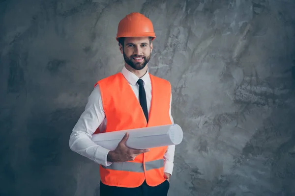 Porträt des positiven professionellen Bauunternehmer Architektur hält seinen Plan für den Bau tragen orangefarbene Helm Uniform isoliert über grauem Hintergrund — Stockfoto