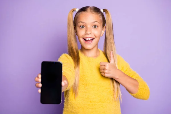 Portrait of funky funny kid hold smartphone show touch screen thumb-up recommend sales promo select suggest gadget wear yellow pullover isolated over violet color background — Stock Photo, Image
