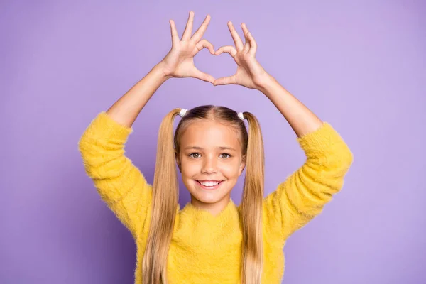 Foto de menina engraçada bonito alegre casual mostrando sinal de forma do coração com os dedos acima de sua cabeça isolado pastel cor violeta fundo — Fotografia de Stock