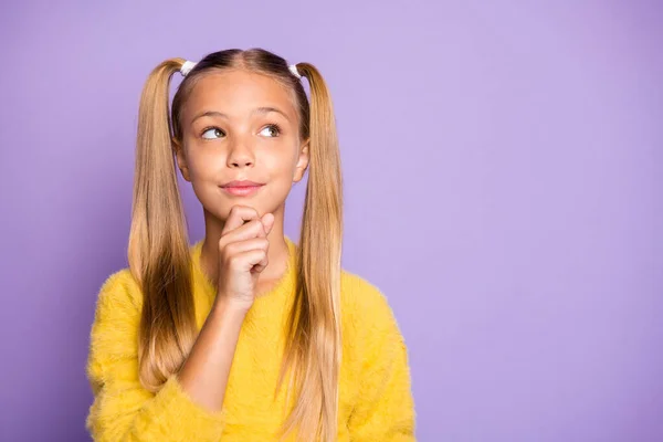 Foto de menina casual pensativo tocando seu queixo usando suéter amarelo olhando para o espaço vazio isolado sobre fundo cor violeta pastel — Fotografia de Stock