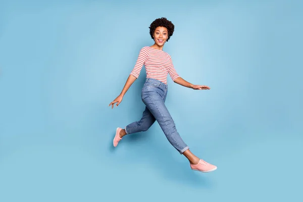 Foto lateral de perfil de longitud completa de dulce niña afro americana alegre salto ir a caminar tienen descanso relajarse usar ropa de estilo casual aislado sobre fondo de color azul —  Fotos de Stock
