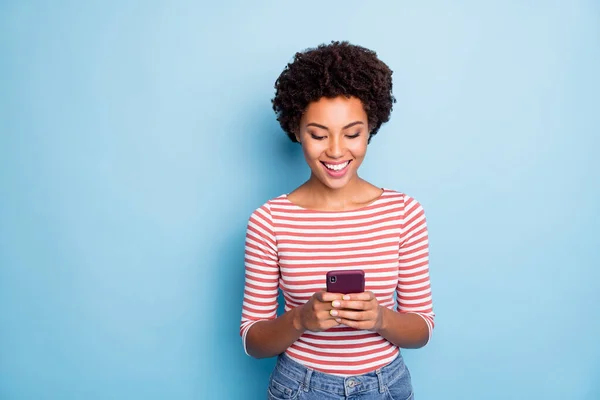 Foto von fröhlichen positiven netten hübschen Mädchen brosing durch Telefon lächelnd zahnlos in Jeans Denim isoliert pastellblauen Farbhintergrund — Stockfoto