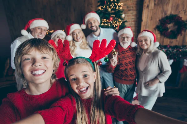 Self photo of large family meeting together with couple of brother sister taking selfie on background of their relatives parents grandparents and Christmas tree in lights — стоковое фото