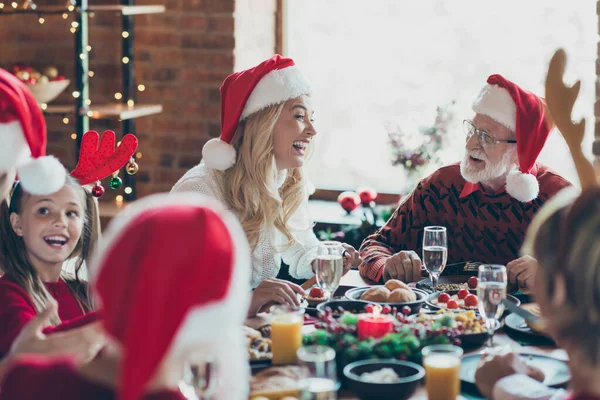 Neşeli, pozitif, sevimli, sevimli, büyük bir ailenin, kız arkadaşı boynuzlu ve Noel Baba şapkalı herkesin yemek yerken birbirleriyle konuştuğu fotoğraf. — Stok fotoğraf