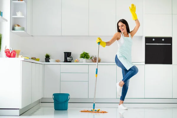 Full length photo of crazy cheerful gilr wash floor in kitchen with mop want have relax fun imagine she dances clubbing raising hands screaming wearing dotted apron indoors — Stock Photo, Image