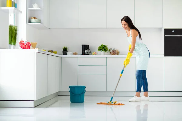 Profile side full size photo of positive cheerful girl having mop washing floor wearing white singlet yellow rubber gloves dotted apron fell content enjoy household chores in kitchen house indoors — ストック写真