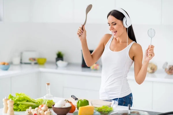 Profile side photo of funny funky house wife wearing headset sing stereo volume song listen music cook tasty healthcare supper in white kitchen house having vegetables eggs cheese tomato