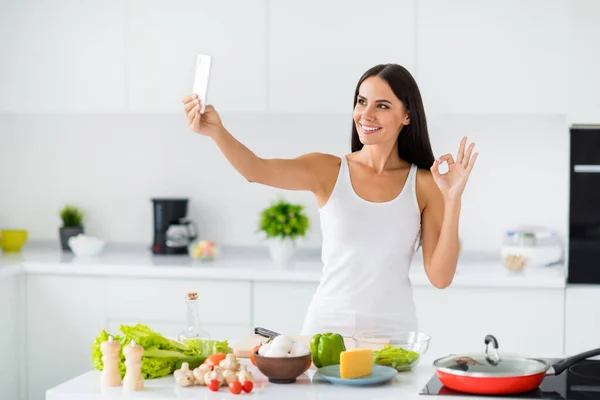 Портрет дружини позитивного будинку кулінарного блогера, який впливає на селфі, показує, як вона готує вечерю охорони здоров'я, затверджує свої органічні інгредієнти, щоб зробити правильний знак на кухні білого будинку — стокове фото