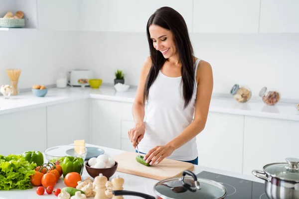 积极女性家庭主妇的画像用厨房用具在室内的木制切菜板上切黄瓜，准备早膳 — 图库照片