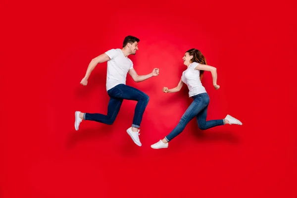 Боковой профиль полный размер тела фото веселой позитивной симпатичной пары парень девушка сталкивается друг с другом прыжки джинсы джинсы белая обувь футболка изолированы яркий цвет фона — стоковое фото