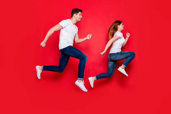 Full length body size side profile photo of cheerful positive running girlfriend boyfriend wearing jeans denim obuv white t-shirt smiling toothily isolated bivid color background jumping — Stock fotografie