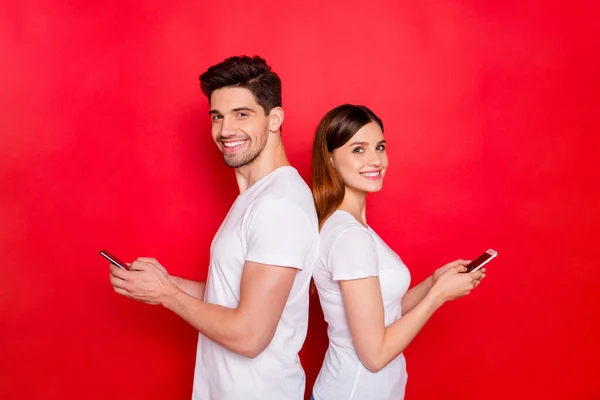 2人の彼女の恋人のカップルの写真一緒に白いTシャツを着てテキストメッセージによってお互いに歯をこして話す笑顔孤立鮮やかな色の背景 — ストック写真