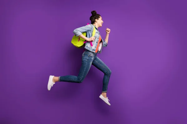 Uzun boylu, güzel bir öğrenci kızın ilk dersten sonra hızla eve atladığını gösteren bir fotoğraf. Yeşil çanta giyin. Sıradan bir kot giyin. — Stok fotoğraf