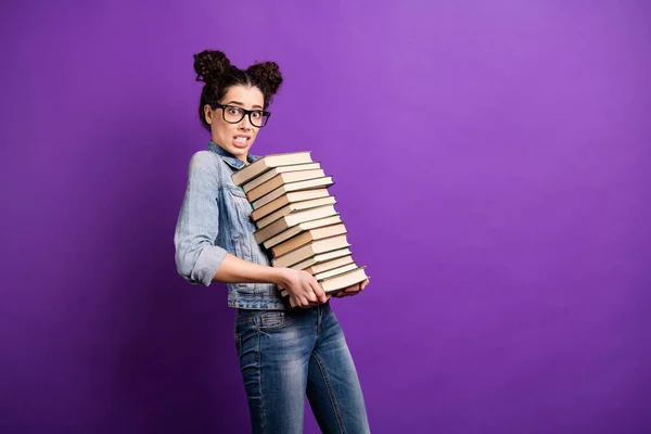 Profil foto av rolig student dam håller många böcker bära litteratur hem tunga bagage panik bära specs casual denim outfit isolerad lila färg bakgrund — Stockfoto