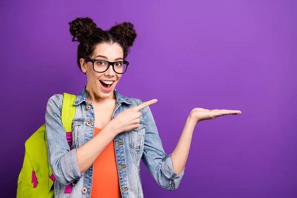 Nahaufnahme Foto von verrückt fröhlich High School Mädchen halten Hand Zeigefinger zeigen akademischen Campus Option tragen Jeans Jacke grüne Rucksack-Brille isoliert über lila Farbhintergrund — Stockfoto