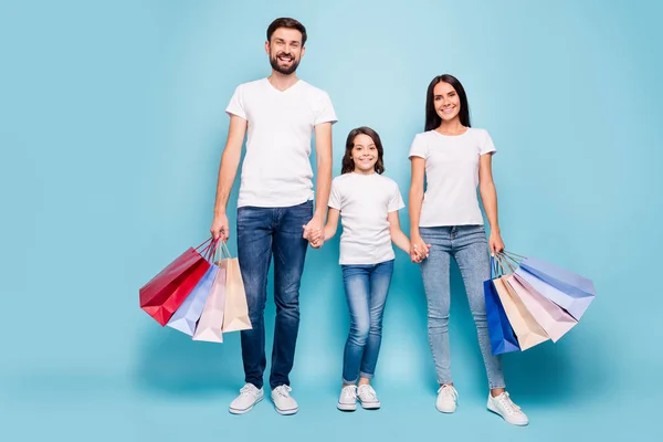 Nueva colección boutique. Foto de tamaño completo de hermoso sueño tres personas mamá papá colegial con pelo marrón tienda al por menor desgaste blanco camiseta vaqueros jeans zapatillas aisladas sobre fondo de color azul — Foto de Stock