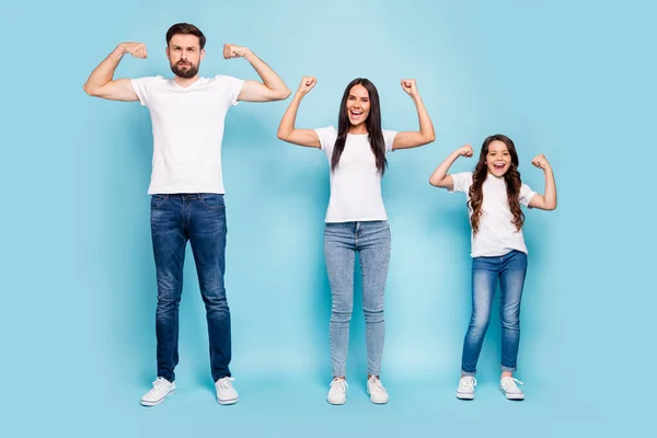 Foto de comprimento total de funky bravo mamãe papai garoto com morena cabelo mostrar tríceps bíceps desfrutar de desgaste entusiástico branco t-shirt jeans tênis isolados sobre fundo de cor azul — Fotografia de Stock