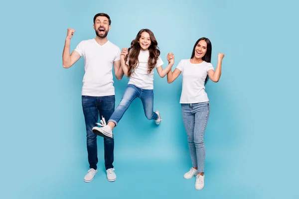 Foto de comprimento total de funky três mãe pai mamãe papai filho cabelo castanho tem festa triunfo levantar punhos gritar sim usar branco t-shirt jeans tênis isolados sobre azul cor de fundo — Fotografia de Stock