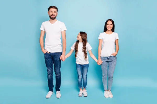 In voller Länge Foto von fröhlich zufrieden drei Menschen mit brünetten Haaren halten Hand genießen Wochenenden tragen weißes T-Shirt Jeans Turnschuhe isoliert über blauem Hintergrund — Stockfoto