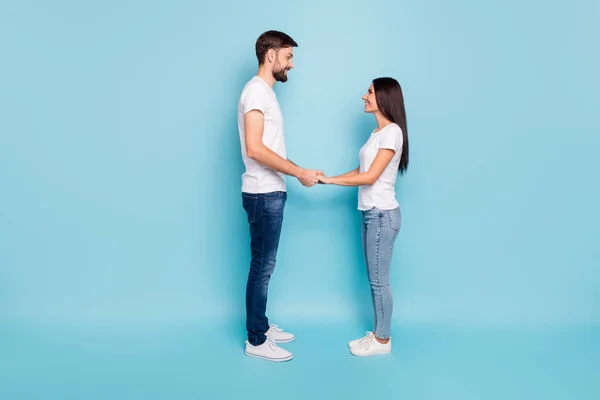 Profil sida full längd foto av uppriktig brunett hår gift sötnosar på smekmånad ha kul helg hålla handen bära vit t-shirt denim jeans sneakers avslappnad stil isolerad över blå färg — Stockfoto