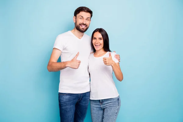 興奮した熱狂的なカップルプロモーターの肖像画は親指アップを示しています選択広告抱擁は青の色の背景に隔離された白いTシャツデニムジーンズ良い外観を着用 — ストック写真