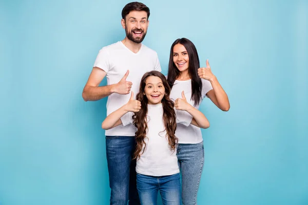 Portret van vrolijke positieve drie brunet haar mensen promoters tonen duim omhoog raden sales dragen witte t-shirt denim jeans casual outfit geïsoleerd over blauwe kleur achtergrond — Stockfoto