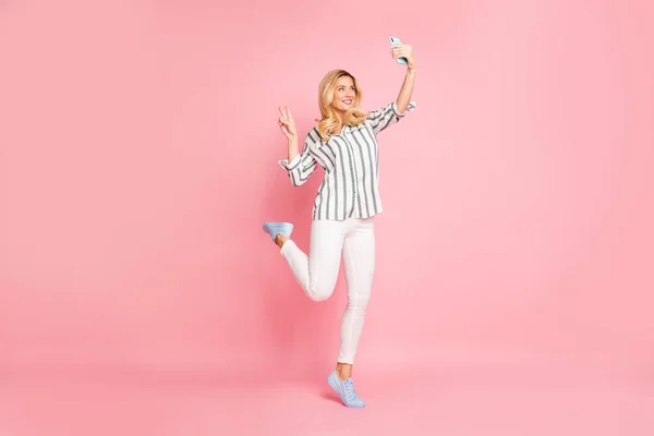 Taille du corps pleine longueur tourné photo de joyeux joli beau blogueur attrayant montrant v-signe prendre selfie portant pantalon blanc isolé couleur pastel arrière-plan — Photo