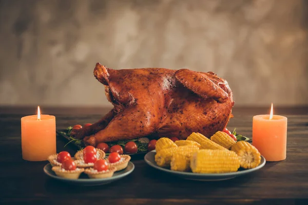 Foto de deliciosa comida de Acción de Gracias festiva de carne asada sabrosa servida con guarnición verde en la mesa de madera tienen callos velas de pastel de tomate rojo aisladas sobre fondo de color marrón — Foto de Stock