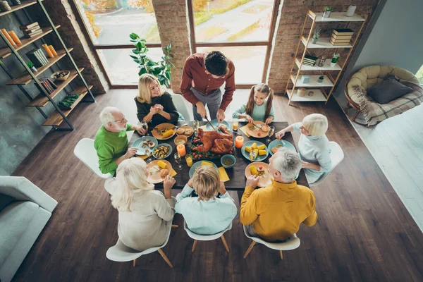 Сверху над высоким углом фото большой зрелой семьи праздновать октябрь День благодарения день сидеть за столом наслаждаться трапезой кукурузы овощи урожай человек нарезки нож жареное мясо блюдо в доме — стоковое фото