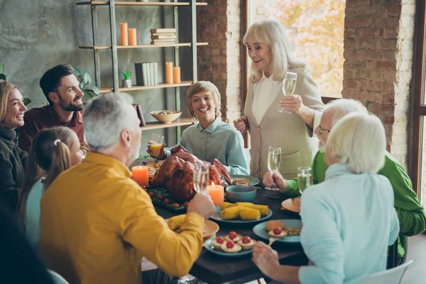 Duża rodzina szczęśliwy dziękczynienie gromadzenia siedzieć stół emerytka kobieta trzymać szampan szklanym toastem za małe dzieci ludzie cieszyć października imprezy ucztowanie z pieczonych dań z kurczaka w domu — Zdjęcie stockowe
