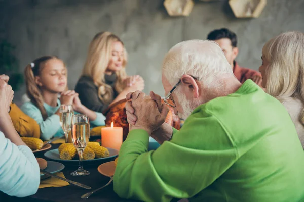 Velká rodina malé děti zralé důchodci setkání na Den díkůvzdání sedací stůl s velkým hostina jídlo pečené maso víno svíčky modlit v domě — Stock fotografie