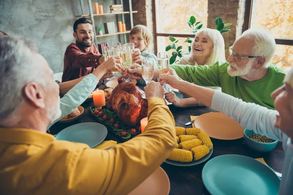 Velká šťastná rodina sedět stůl oslavit říjen dovolená díkůvzdání den držet sklenici šampaňského cinknout mají jídlo kukuřice sklizeň pečené maso shromažďování malých dětí důchodci v domě — Stock fotografie