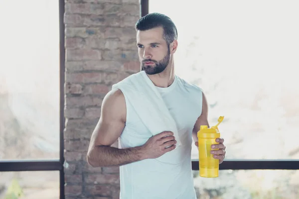 Foto de chico deportista guapo terminó el entrenamiento matutino beber agua dulce sosteniendo toalla buscando lado concentrado ropa deportiva tanque-top entrenamiento casa estudio ventanas interiores —  Fotos de Stock